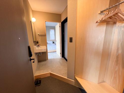 a hallway leading to a bathroom with a sink at 日々の宿 ひねもす in Tamano
