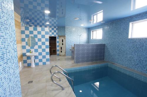 baño de azulejos azules con bañera y lavamanos en Hotel Salem en Aktau