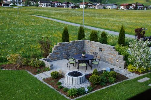 a garden with a table and chairs and a brick wall at Haus Gaby in Holzgau