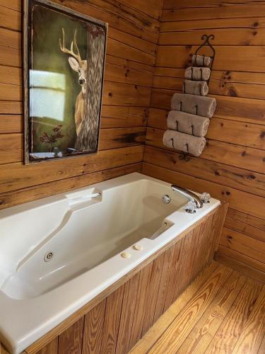 a bath tub in a wooden bathroom with a deer picture at Log Cabin in Bailey Camp