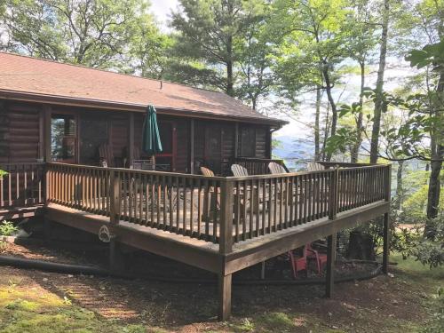 a cabin with a large wooden deck with chairs at Log Cabin in Bailey Camp