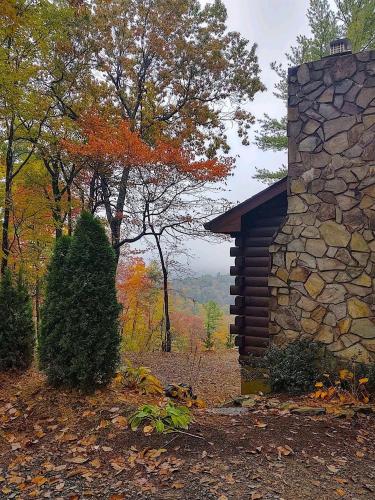 a log cabin with a stone wall and trees at Log Cabin in Bailey Camp
