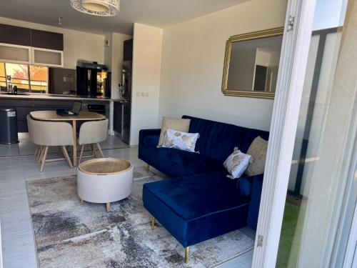 un salon avec un canapé bleu et une table dans l'établissement Appartement entièrement meublé de 57m Chanteloup les vignes Centre ville, à Chanteloup-les-Vignes