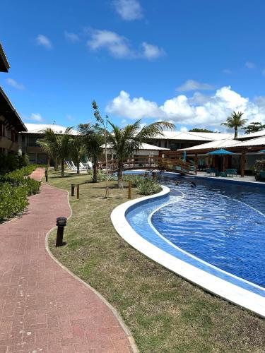 a swimming pool next to a resort with palm trees at Itacimirim Bioflora in Itacimirim