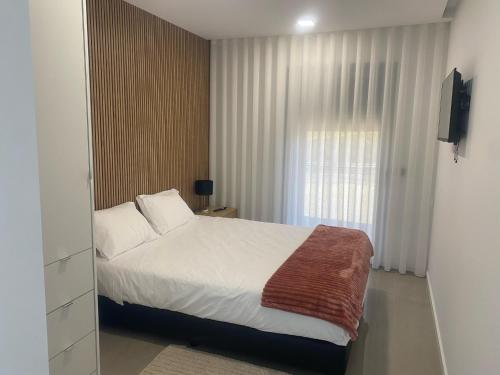 a bedroom with a white bed and a window at Cantinho do Silvano in Gimonde