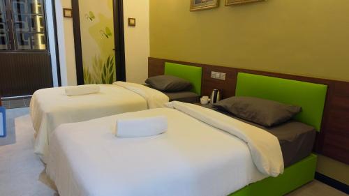 three beds in a room with green and white at D GAYA HOTEL Cameron Highlands in Tanah Rata