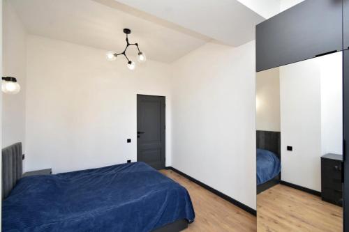 a bedroom with white walls and a blue bed at Komitas Comfort and Charm in Yerevan