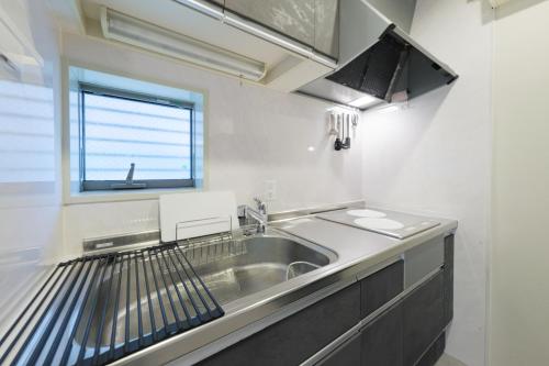 a kitchen with a stainless steel sink and a window at Make Your Hotel幡ヶ谷 in Tokyo