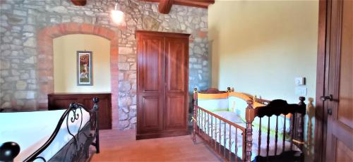 a bedroom with a crib and a stone wall at CAMPO AL VENTO - Country farm in Monte Castello di Vibio