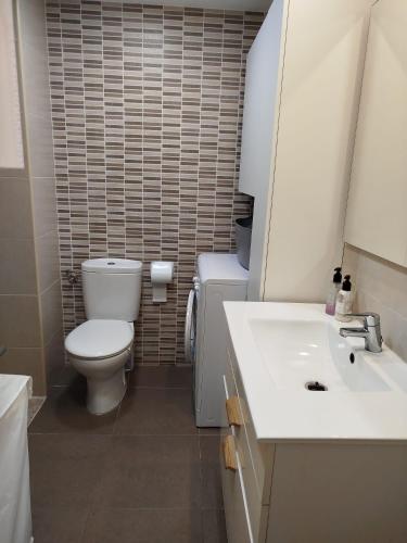 a white bathroom with a toilet and a sink at Cullera Playa de los Olivos Apartment in Faro de Cullera