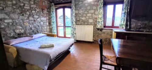 a bedroom with a bed and a table and windows at CAMPO AL VENTO - Country farm in Monte Castello di Vibio