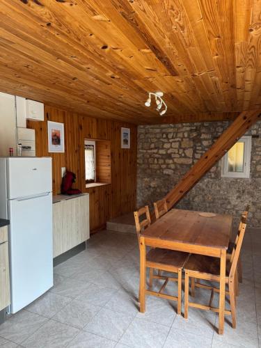 Il comprend une cuisine dotée d'un plafond en bois, d'une table et d'un réfrigérateur. dans l'établissement Gîte de Fertés, à Amarens
