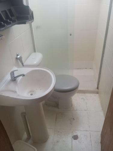 a white bathroom with a toilet and a sink at La Casa del Monica in Itacaré