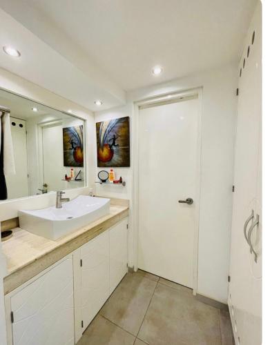 a white bathroom with a sink and a shower at Caribbean apartment in Cancún