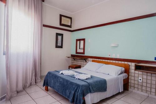a bedroom with a bed with a blue blanket at Hotel São Charbel in Ubatuba