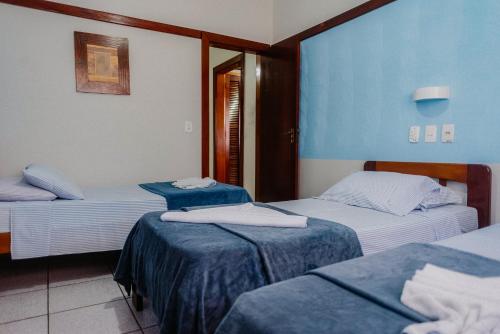 a room with three beds with blue and white at Hotel São Charbel in Ubatuba
