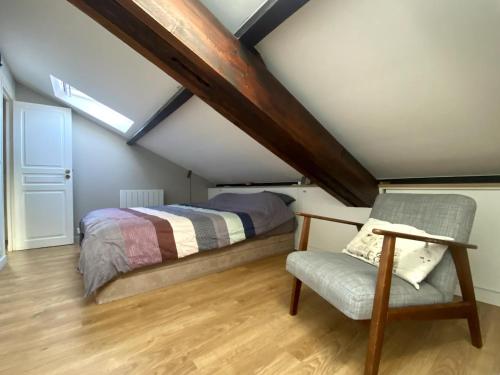 une chambre mansardée avec un lit et une chaise dans l'établissement Beautiful Duplex, à Issy-les-Moulineaux