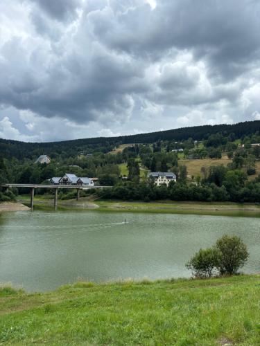 a body of water with a bridge in the background at ALPINA Mountain View Apartment in Špindlerův Mlýn