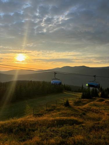 two gondolas on a ski lift with the sun in the background at ALPINA Mountain View Apartment in Špindlerův Mlýn