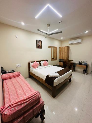 a bedroom with a bed and a bench in it at Hotel Gokulam Grand in Pithāpuram