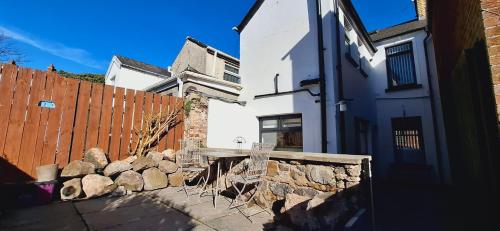 a white house with a stone wall and a fence at Home away from home in Belfast