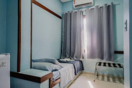 a small room with a bed and a window at Hotel São Charbel in Ubatuba