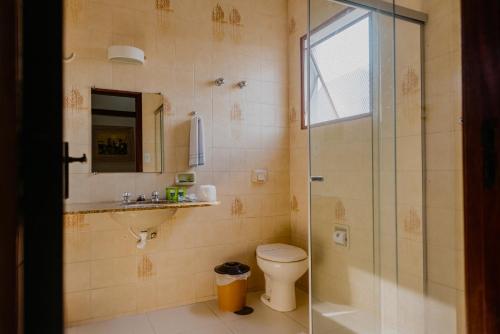 a bathroom with a shower and a toilet and a sink at Hotel São Charbel in Ubatuba