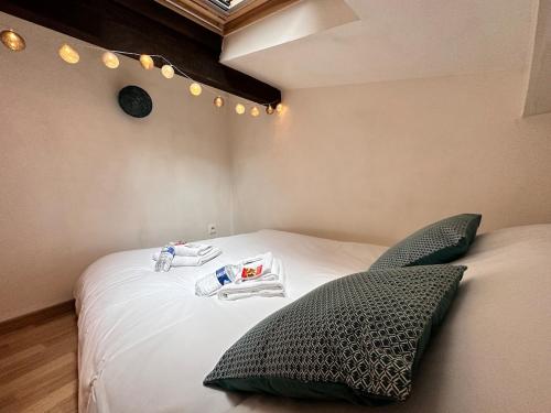 une chambre avec un grand lit blanc avec des oreillers dans l'établissement Carreret chic et cocon proche centre ville, à Reims