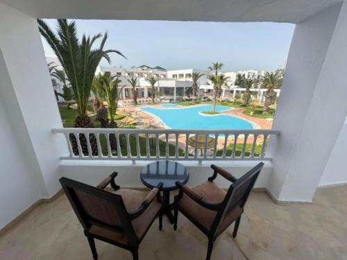 a balcony with a table and two chairs and a pool at Hello Yasmine Hotel in Hammamet