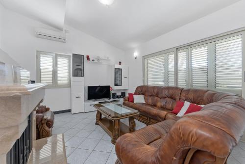 a living room with two leather couches and a television at Villa Almas with swimming pool, tennis court, sauna, gym, grill house in Neorić