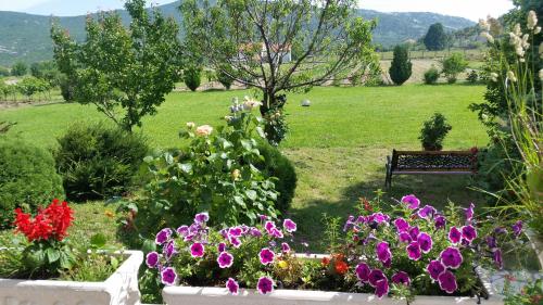 a garden with flowers and a bench in a field at Villa Almas with swimming pool, tennis court, sauna, gym, grill house in Neorić