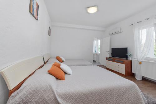 a white bedroom with two beds and a television at Villa Almas with swimming pool, tennis court, sauna, gym, grill house in Neorić
