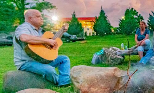 a man playing a guitar in a park at Arbors at Island Landing Hotel & Suites in Pigeon Forge
