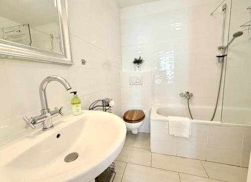 a white bathroom with a sink and a toilet at BELLE KITZ PURE im Zentrum by Belle Stay in Kitzbühel