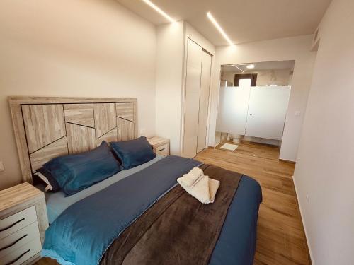 ein Schlafzimmer mit einem großen Bett mit einem hölzernen Kopfteil in der Unterkunft Claudia Luxury Apartment near the beach with a pool, gym, and secure gated parking in Arenales del Sol
