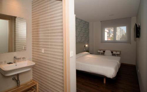 a bedroom with a bed and a sink and a mirror at Pensión Boutique ADMERA in Santiago de Compostela