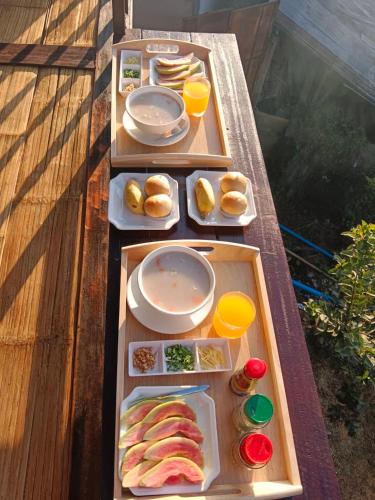 a wooden table with three trays of food on it at บ้านปันสุข ผาหมี in Ban Pha Mi