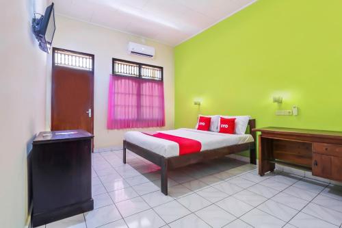 a bedroom with a bed in a green wall at OYO 2184 Nan Berlian Inn in Legian