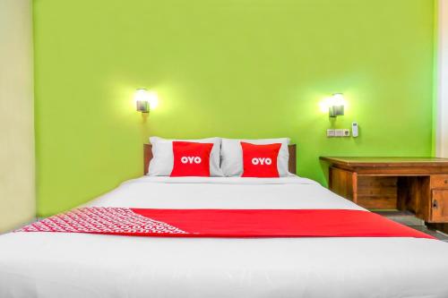 a bedroom with a large bed with two red pillows at OYO 2184 Nan Berlian Inn in Legian