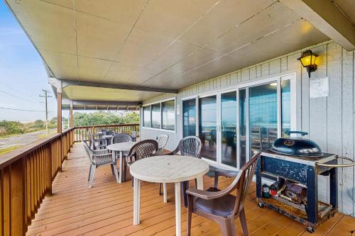 a balcony with tables and chairs and a grill at Falcon's Nest in Twin Rocks