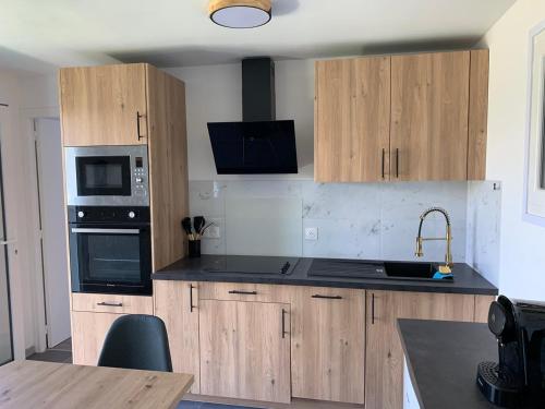 - une cuisine avec des placards en bois et des appareils noirs dans l'établissement Maisonnette de Michelle - Peace and quiet, à La Gaude