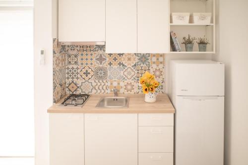 a white kitchen with a sink and a refrigerator at Apartmani Adrijan Krk in Krk