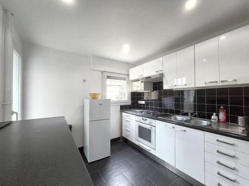 une cuisine avec des armoires blanches et un comptoir noir dans l'établissement Large T2 50m from the beaches, à Nice