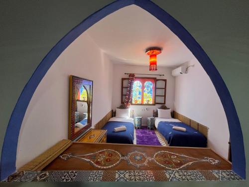 an arched room with two beds and a mirror at Casa Blue Star in Chefchaouene