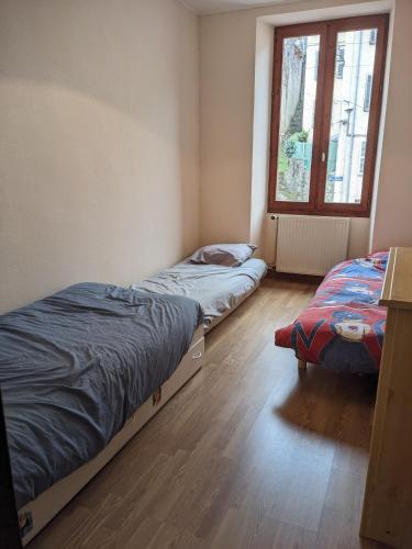 deux lits assis dans une pièce avec une fenêtre dans l'établissement Appartement et salle de jeu, à Saint-Claude