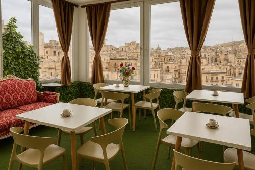 a restaurant with tables and chairs and windows at Jessica Flat Malta Royal Guesthouse in Cospicua