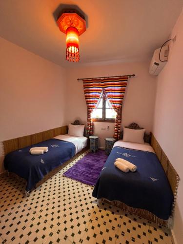a bedroom with two beds and a window and a chandelier at Casa Blue Star in Chefchaouene