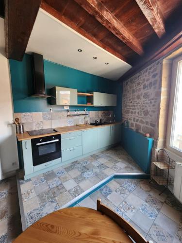- une cuisine avec des murs bleus et un mur en pierre dans l'établissement Charmant T2 à proximité du métro Valmy, à Lyon