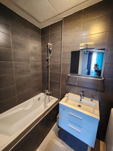 une salle de bain avec un lavabo, une baignoire et un miroir dans l'établissement Charmant T2 à proximité du métro Valmy, à Lyon