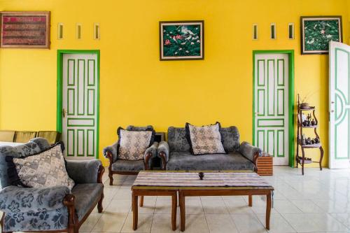 a living room with two couches and a yellow wall at Hotel O Villa Tirta Melati Syariah in Banjar